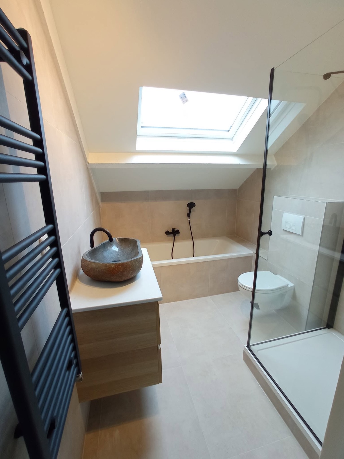 Opgeleverde badkamer met bad onder het dakraam